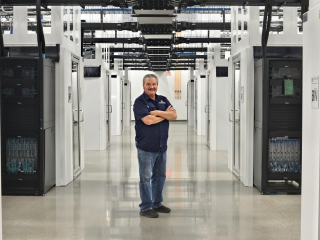 photograph of man with servers at a data center